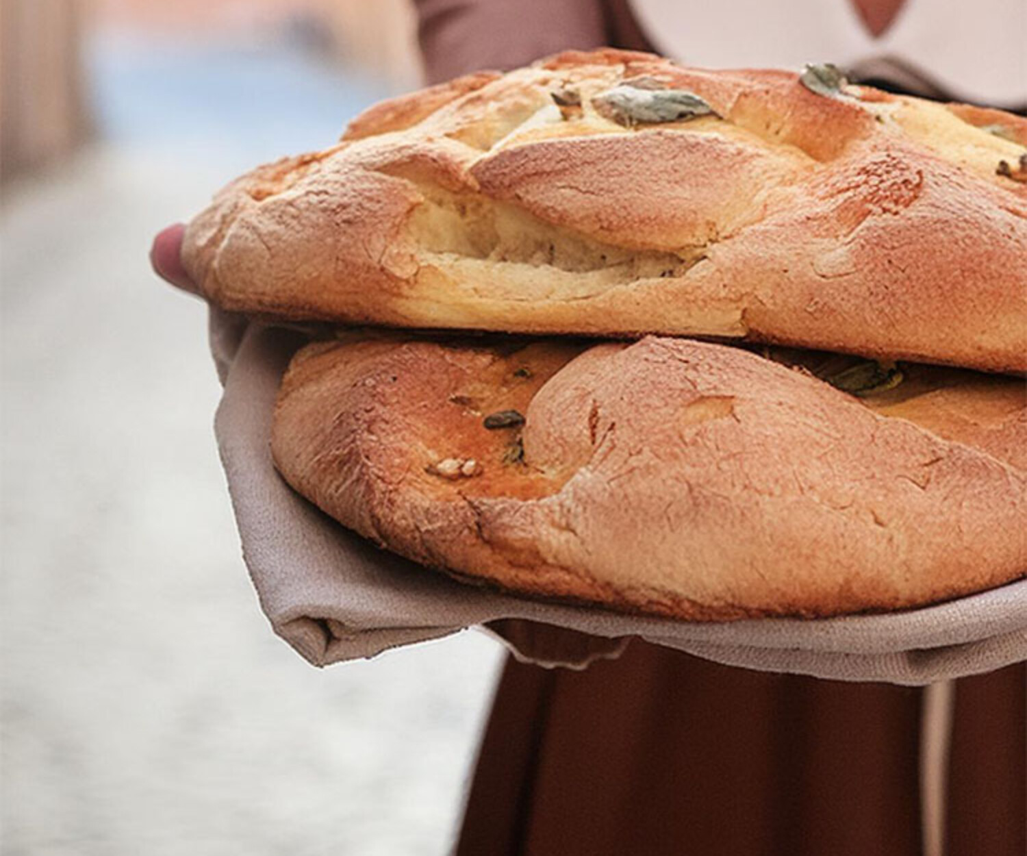 Hintergrundbild für Corporate Design von Bäckerei il Panetto zeigt eine Frau auf Straßen von Italien mit Lächeln und frischgebackenem Brot und einem Logo in der Ecke