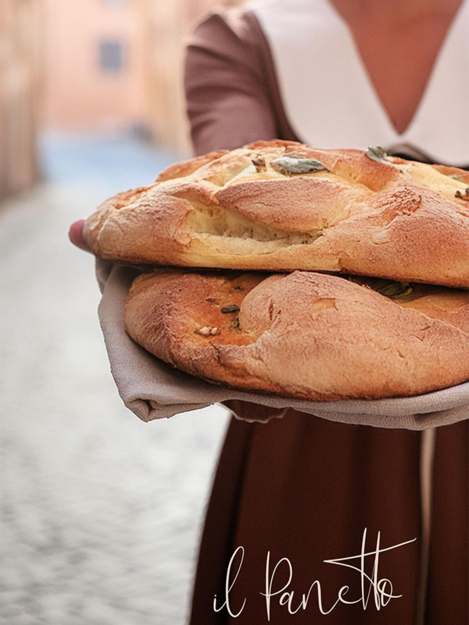 Hintergrundbild für Corporate Design von Bäckerei il Panetto zeigt eine Frau auf Straßen von Italien mit Lächeln und frischgebackenem Brot und einem Logo in der Ecke